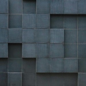 Close-up of a modern building facade with grey geometric tiles and vent panels.